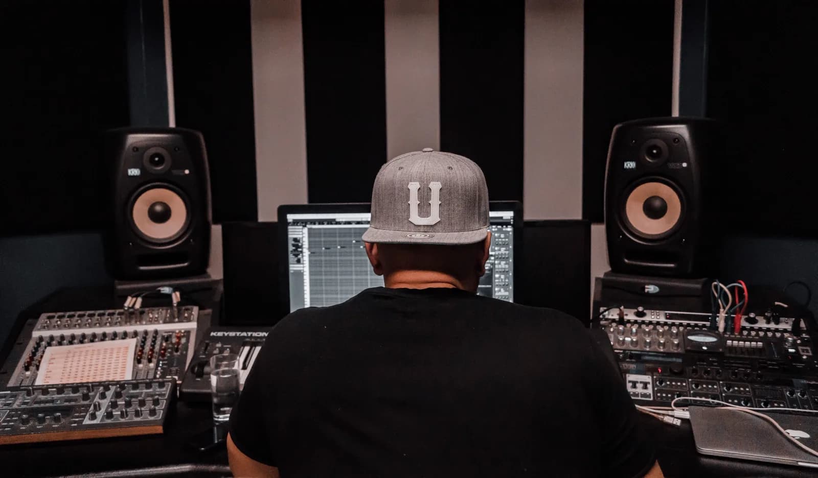 Producer at a mixing desk between studio monitors, seen from behind